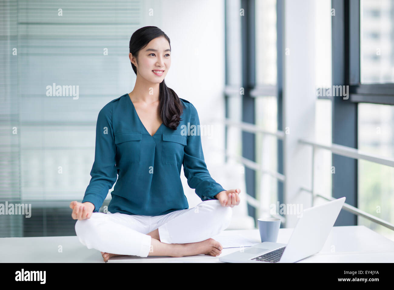 Young Businesswoman Doing Yoga On Office Desk Stock Photo