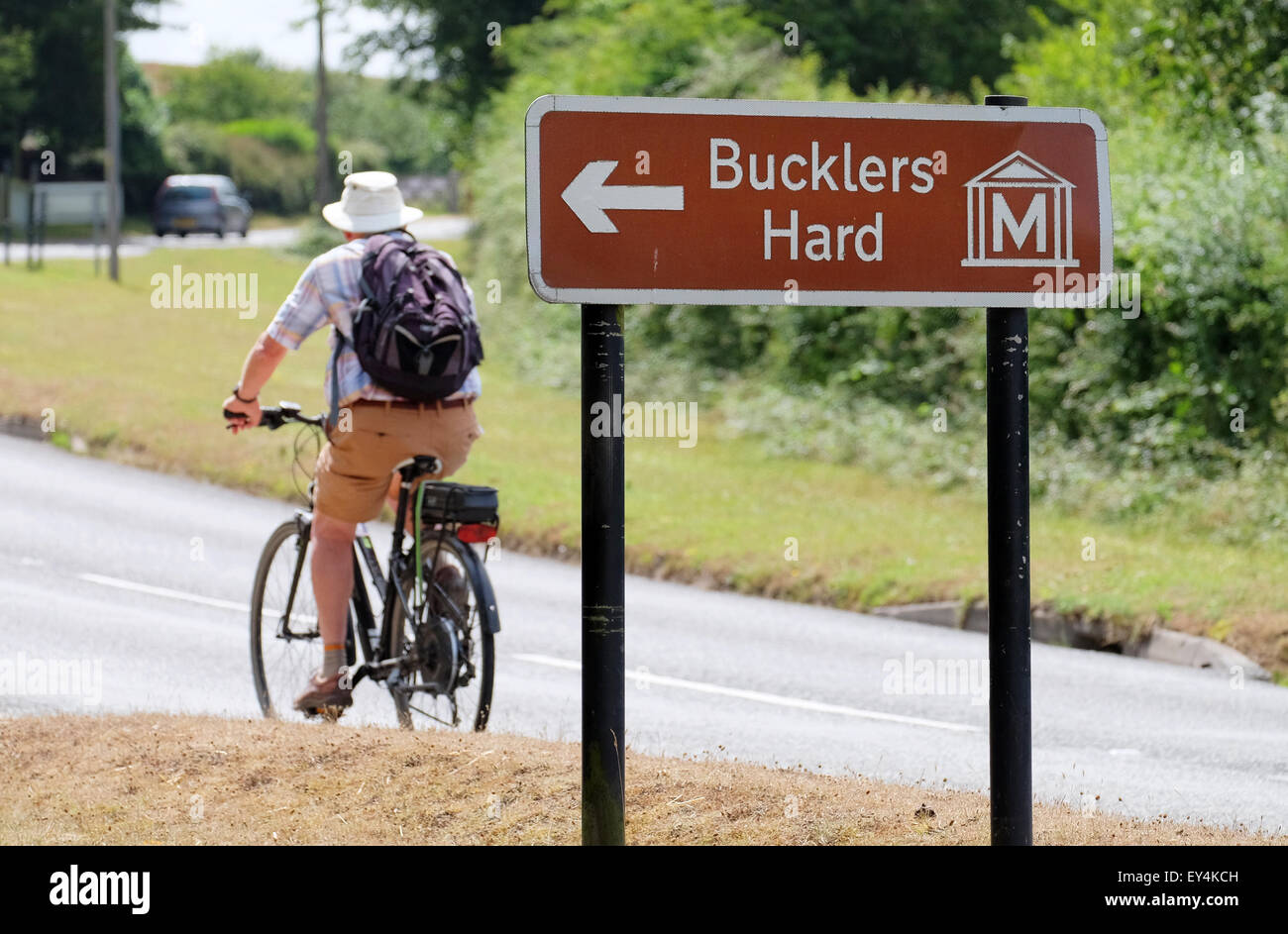 A cyclist passes a Buckler's Hard road sign in Beaulieu Hampshire UK Stock Photo
