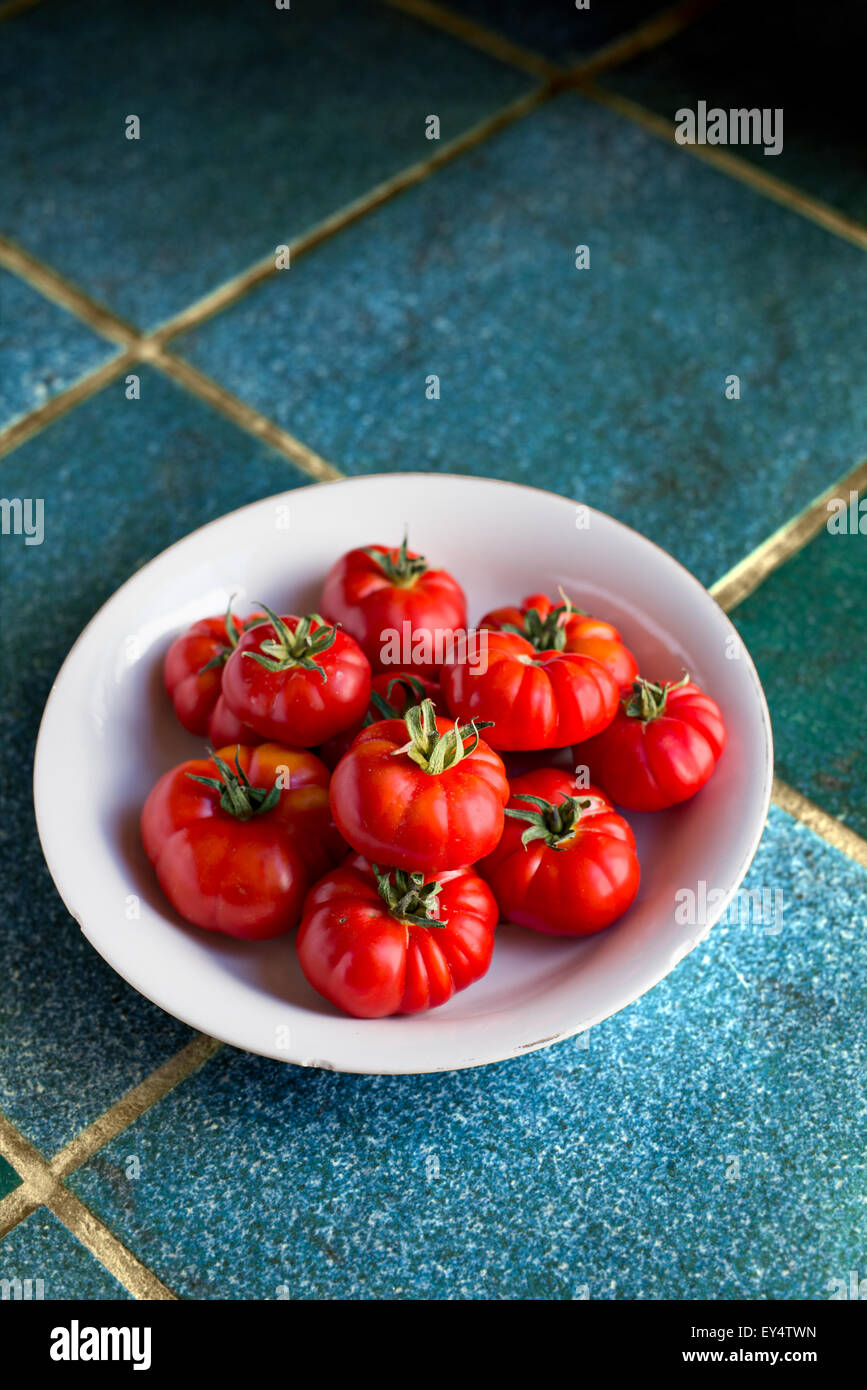 Fresh organic tomatoes in a rustic set. Stock Photo