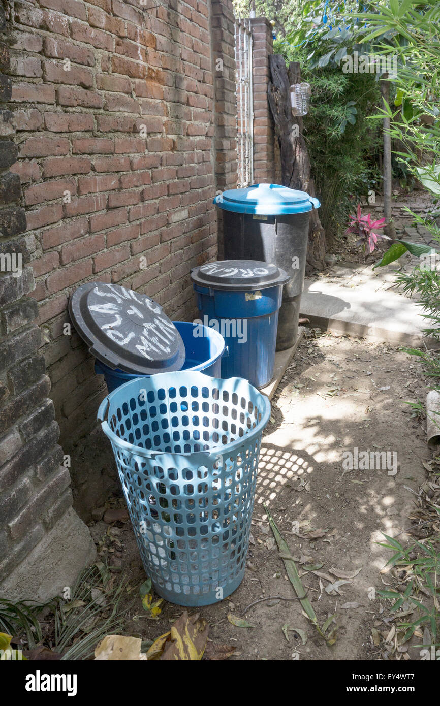 empty various size blue plastic labelled recycling tubs lined up neatly along an old brick wall