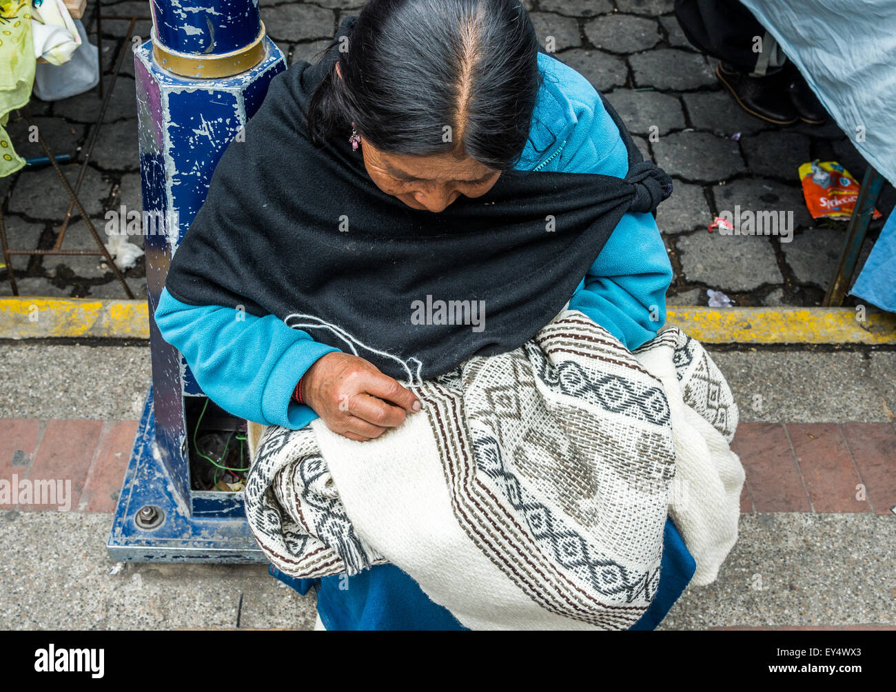 A native woman hand knits a sweater at local market. Otavalo, Ecuador. Stock Photo