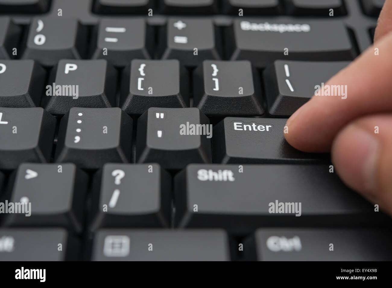 hitting the enter key of a black keyboard Stock Photo