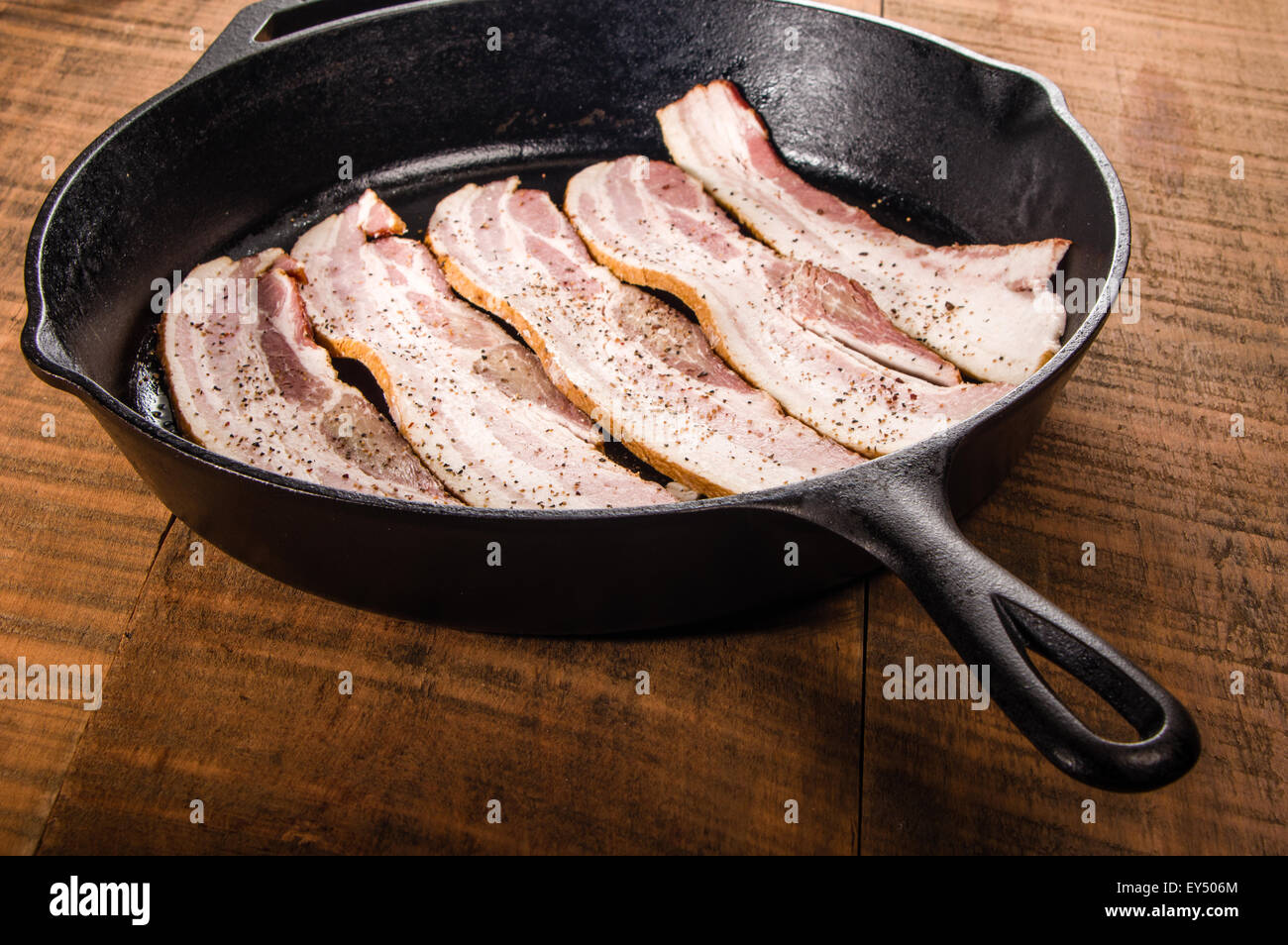Cast iron skillet with strips of raw bacon ready to fry Stock Photo Alamy