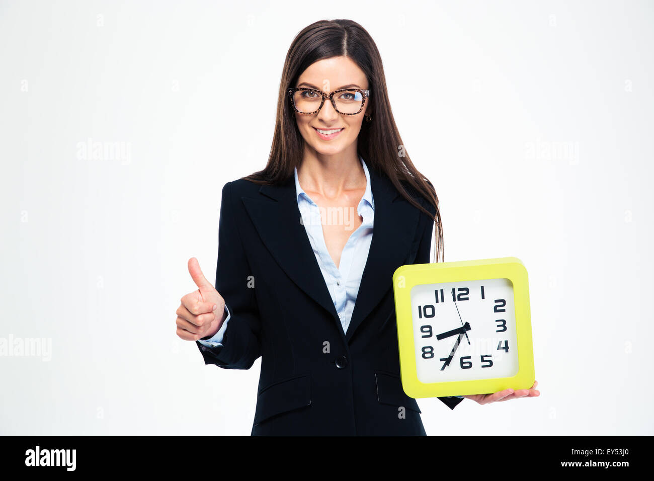 Smiling businesswoman holding clock and showing thumb up isolated on a white background Stock Photo
