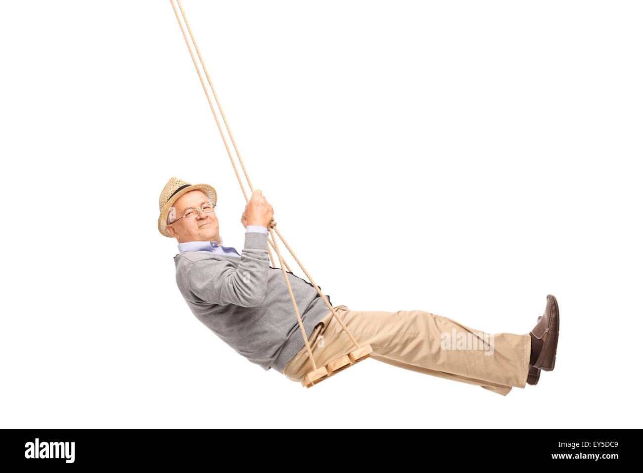 Carefree senior man swinging on a wooden swing and looking at the camera isolated on white background Stock Photo