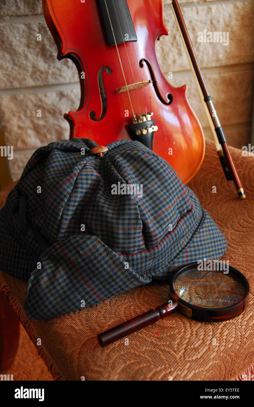 A deerstalker hat, a magnifying glass and a violin set a 'Sherlockian' scene Stock Photo