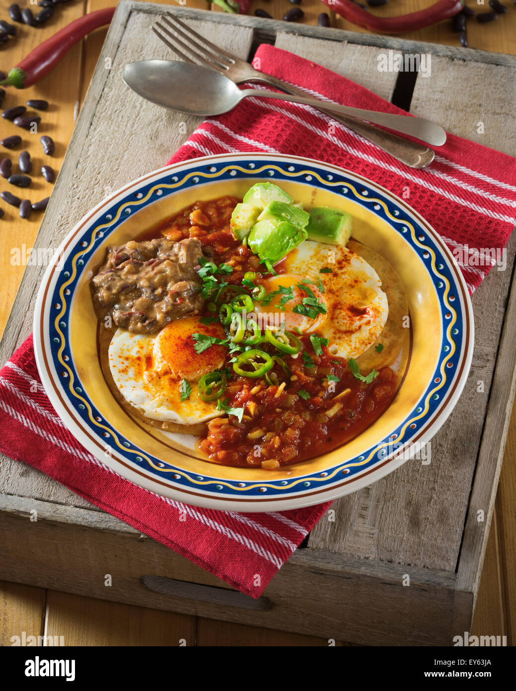 Huevos rancheros. Fried eggs on tortillas with tomato chilli sauce and refried beans Stock Photo