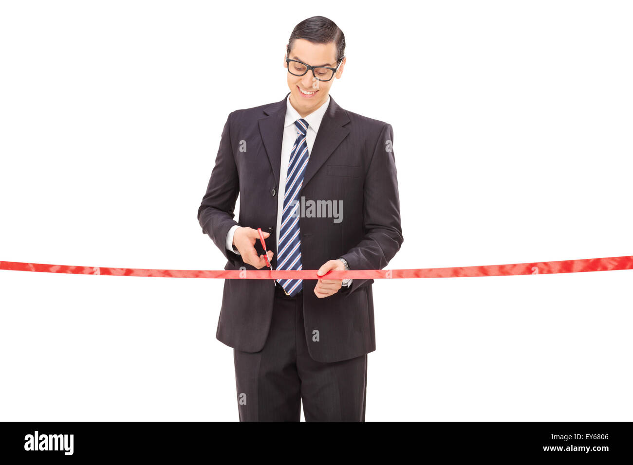 Joyful young businessman cutting a red ribbon with scissors isolated on white background Stock Photo