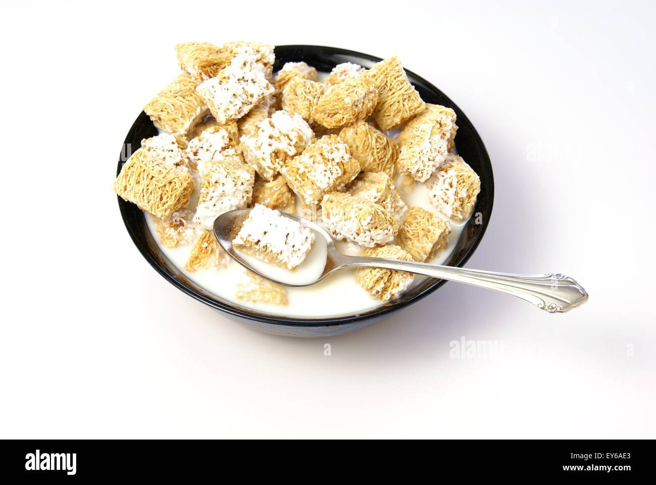 Cold breakfast cereal. Wheat squares with frosting in milk Stock Photo