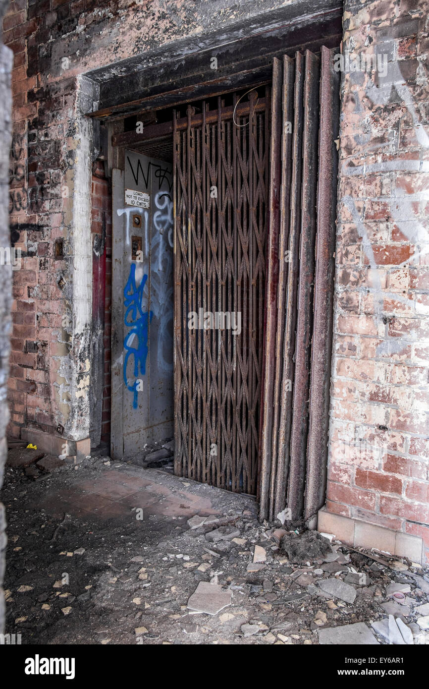 Concertina metal gates on an old lift with graffiti on the walls and