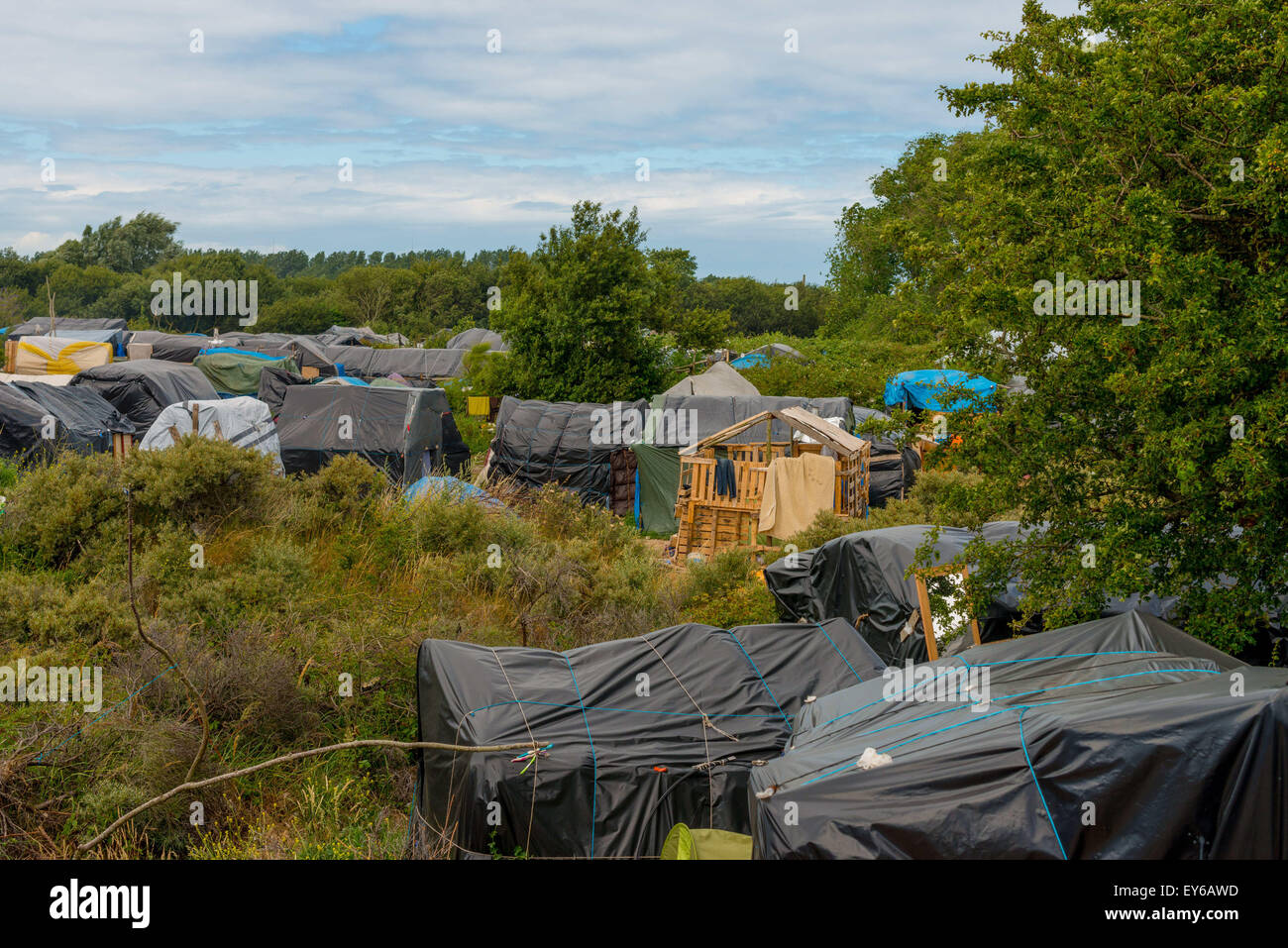Calais, France. 22nd July, 2015. Refugees from Afghanistan, Syria, Sudan, and Eritrea steadily descend on a migrant camp in the French coastal town of Calais. They hope to gain entry to the UK, just 21 miles away across the English Channel. But in May, French police destroyed their camp and told the migrants to go elsewhere. And so they moved. across the street. (Credit Image: © Velar Grant via ZUMA Wire) Credit:  ZUMA Press, Inc./Alamy Live News Stock Photo