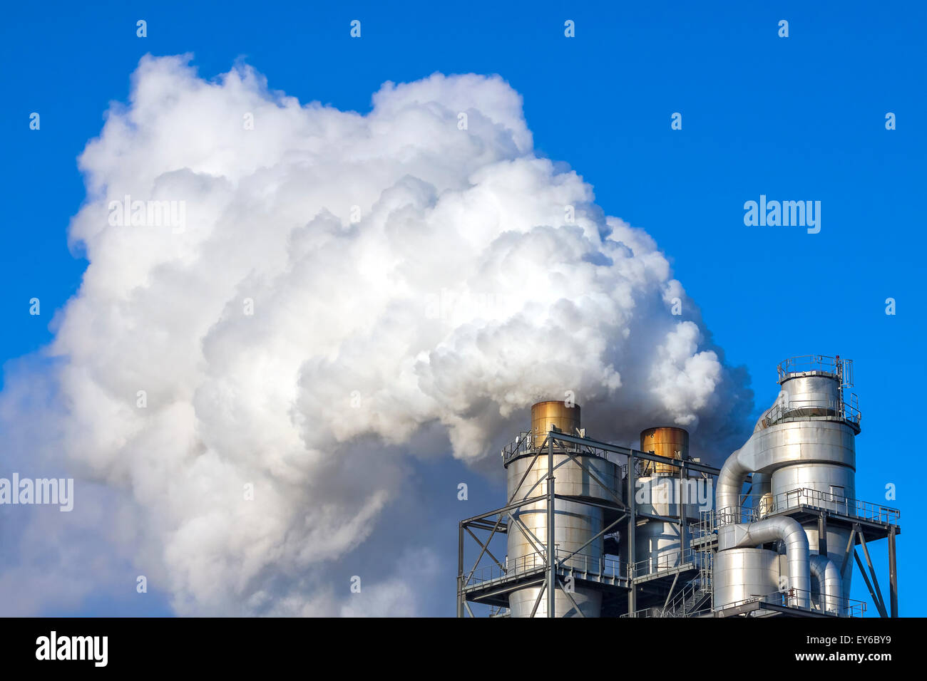 Smoke clouds from a chimney against blue sky, environment pollution concept. Stock Photo