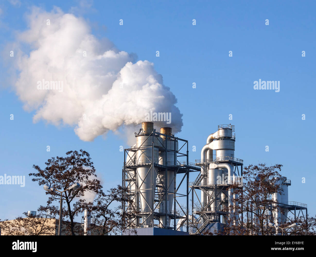 Smoke clouds from a chimney against blue sky, environment pollution concept. Stock Photo