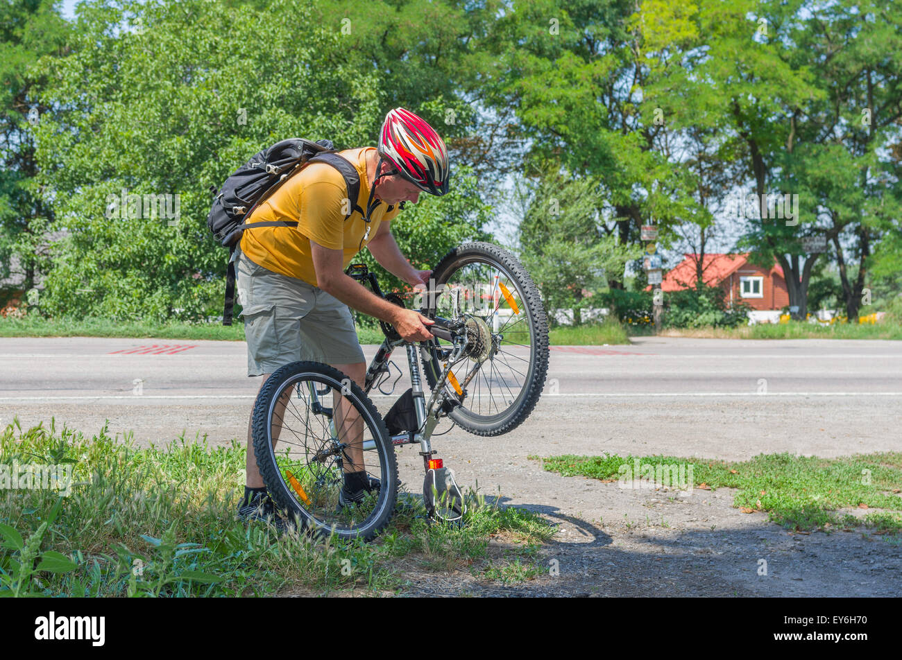 Mature cyclist having repair on the road Stock Photo