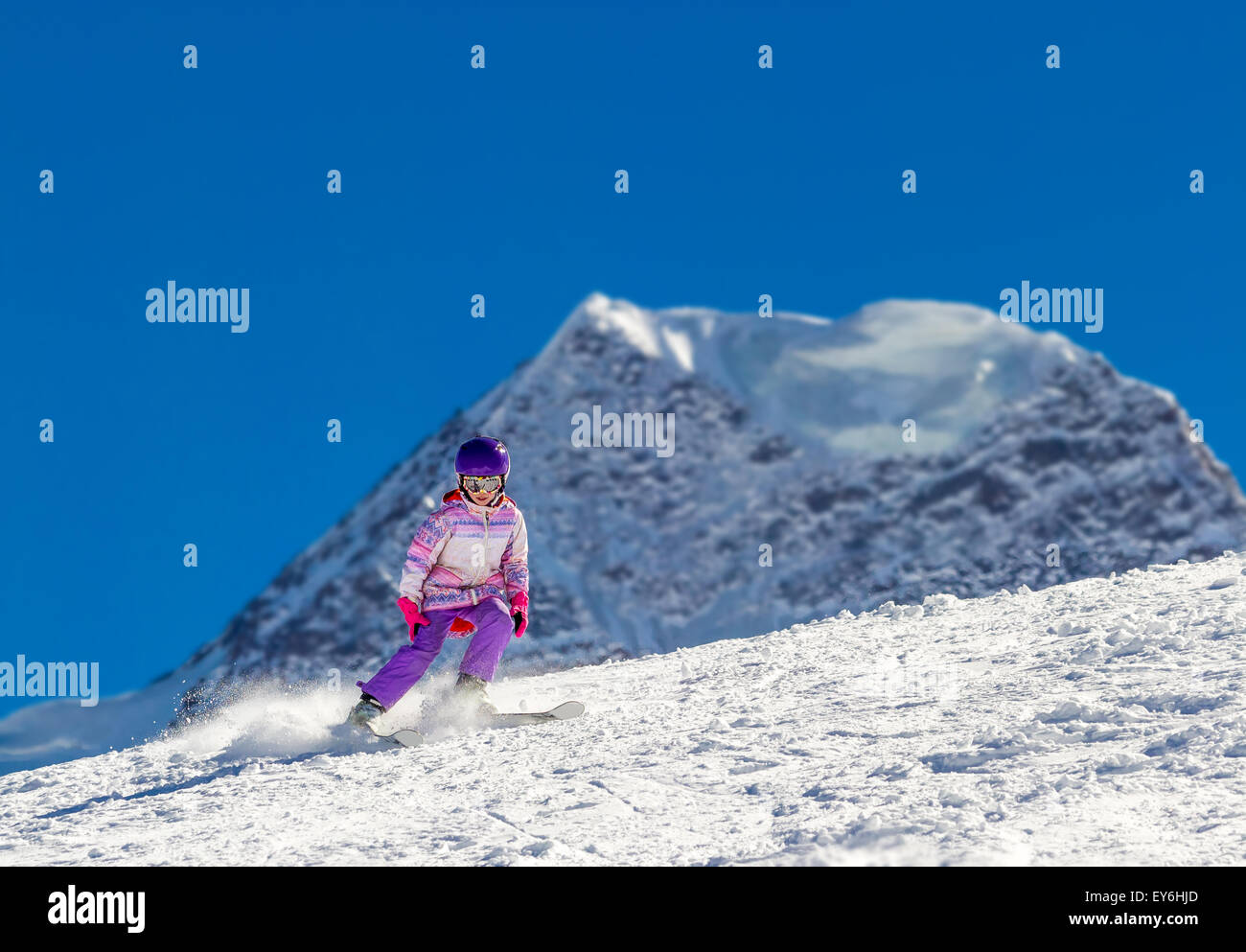 Little skier in high mountains. Against the background of high mountains covered with ice Stock Photo