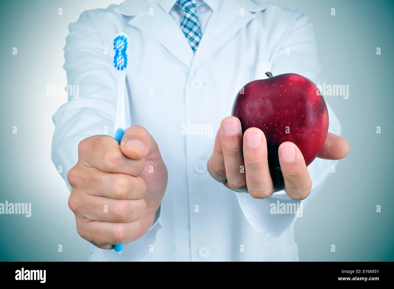 a dentist showing a toothbrush and an apple depicting the importance of