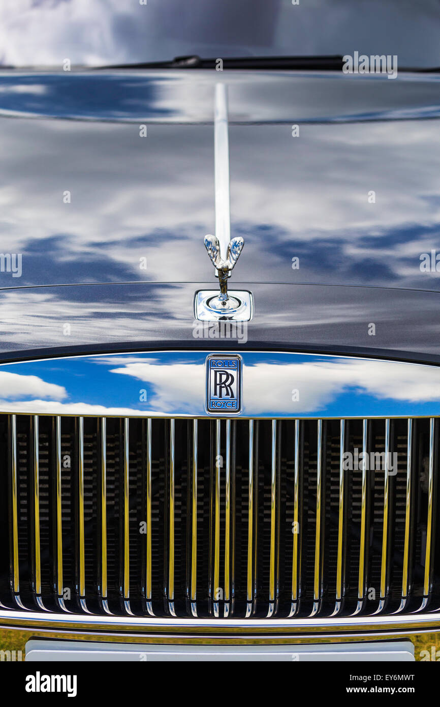 The Spirit of Ecstasy is the name of the Rolls Royce's famous car mascot. Blue sky and clouds are reflected in the car's grille. Stock Photo