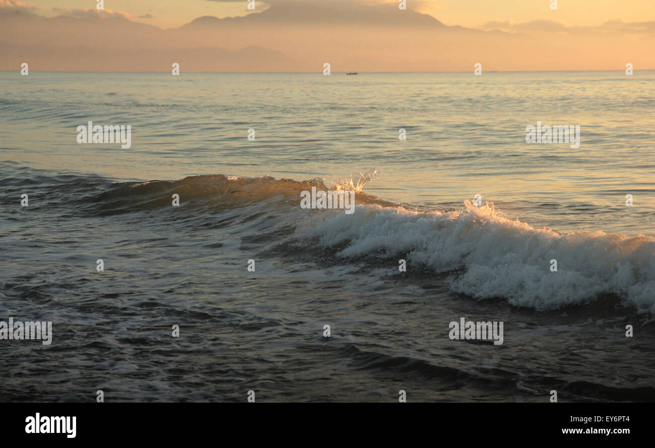 Waves at sunrise, with early morning fog clinging to the horizon in the distance. Stock Photo