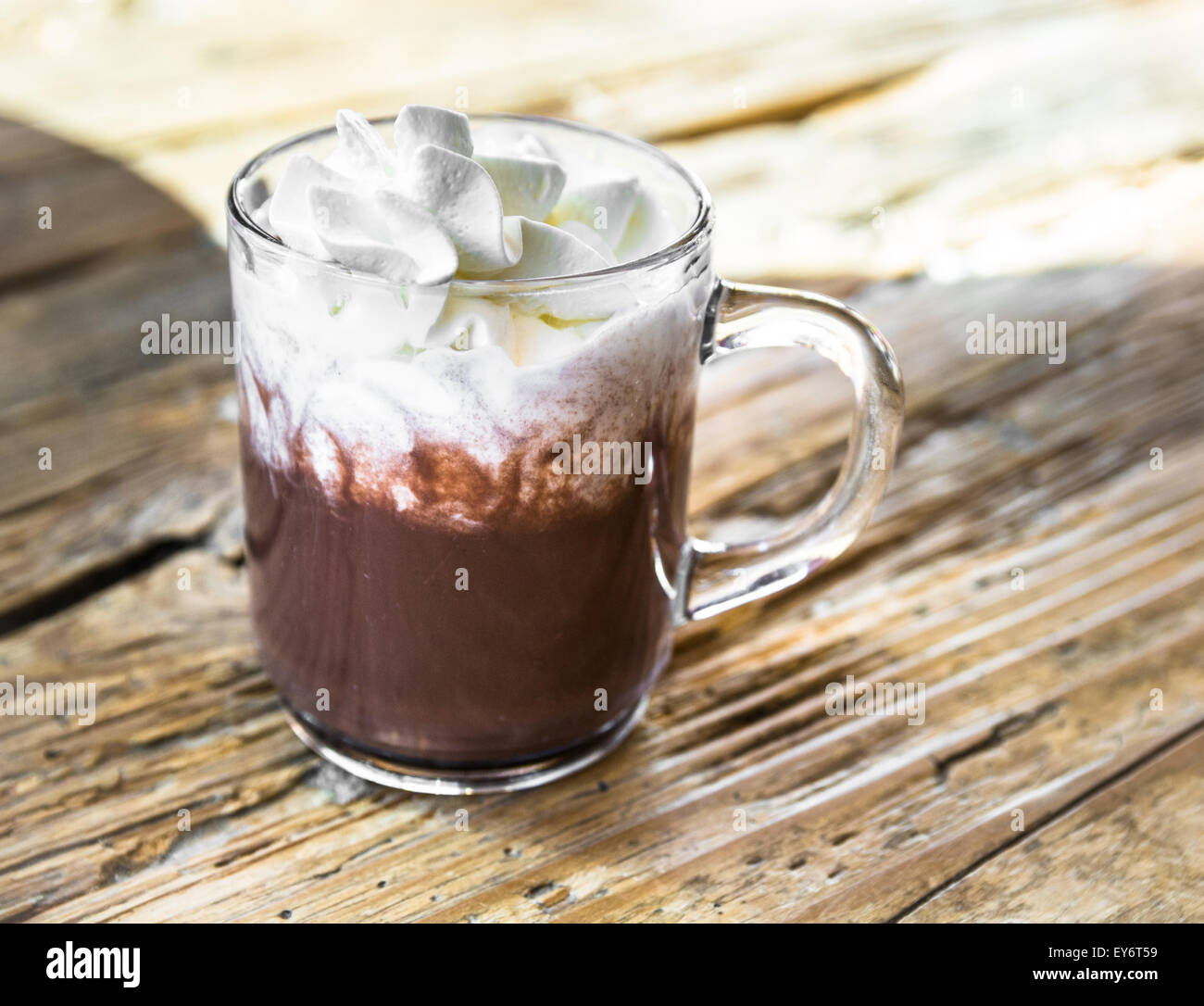 chocolate drink with whipped cream in transparent cup on rough wooden table Stock Photo