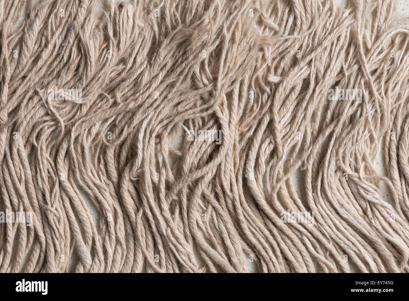Tassels of hand woven rug worn and wavy on marble stone as an edge difference in weave fringe