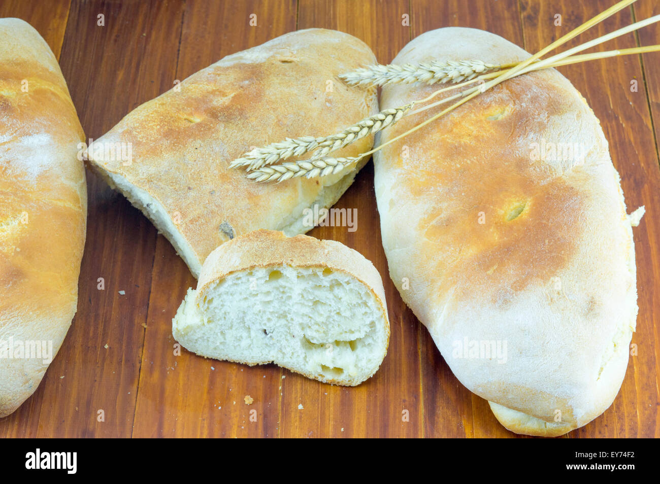 Cut homemade bread on a table decorated with wheat Stock Photo