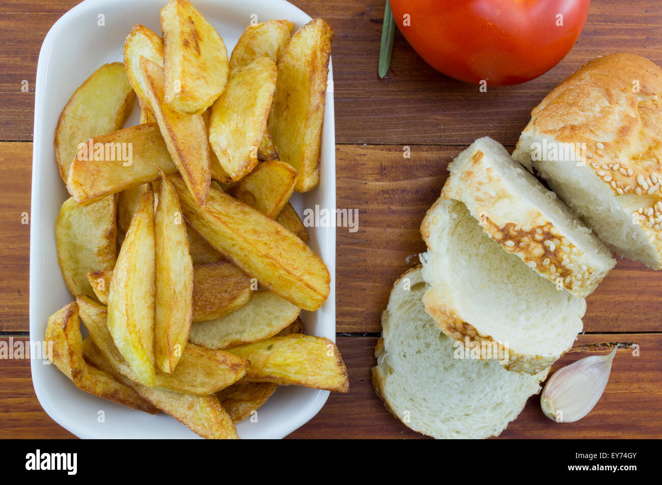 Homemade fried potatoes on a plate decorated with sliced bread, onion, and a tomato Stock Photo