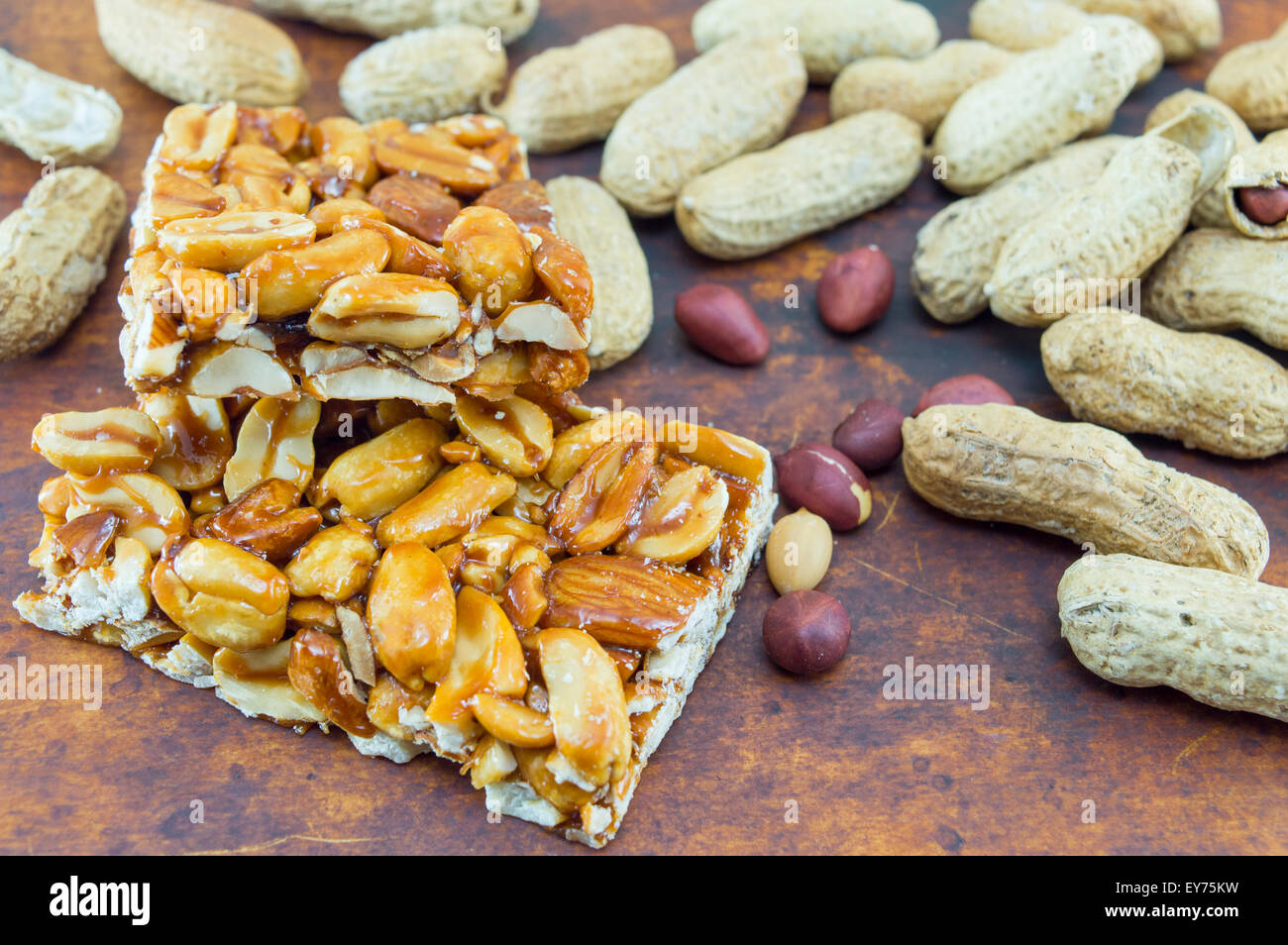 Honey bar with peanuts almonds and hazelnuts surrounded by bunch of