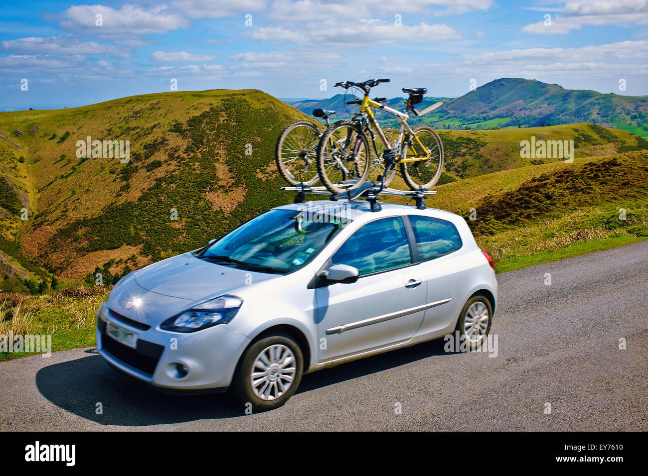 A moving car with two bicycles on the roof rack driving across the Shropshire Hills in England, UK. Stock Photo