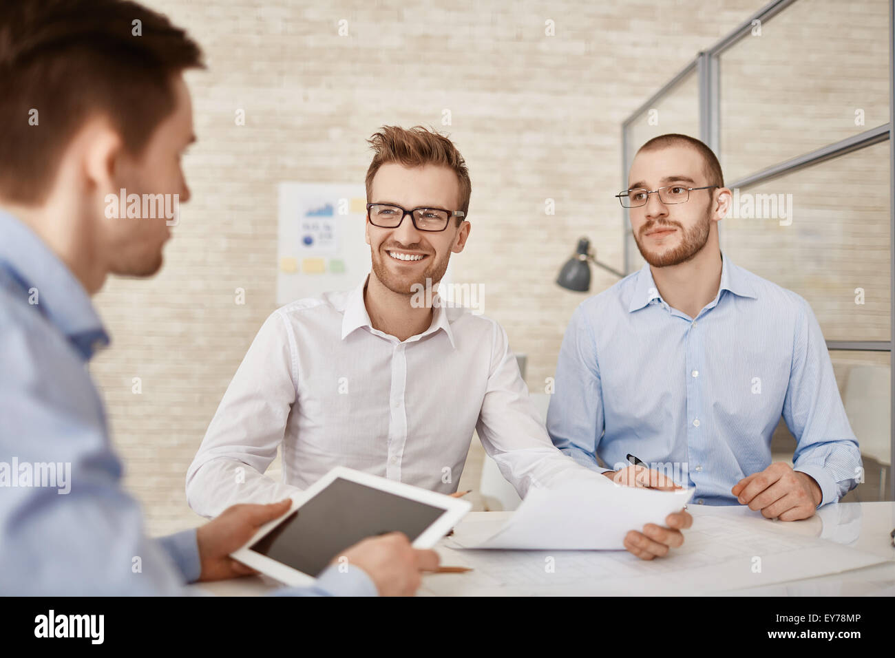 Three businessmen discussing plans and strategies at meeting Stock Photo