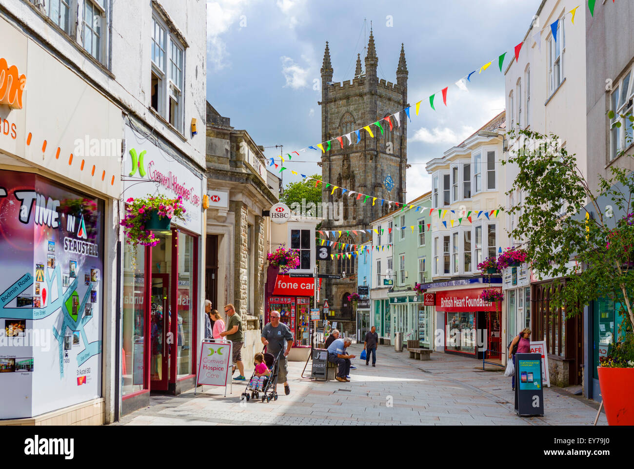 Shops on Fore Street in the town centre looking towards Holy Trinity Church, St Austell, Cornwall, England, UK Stock Photo