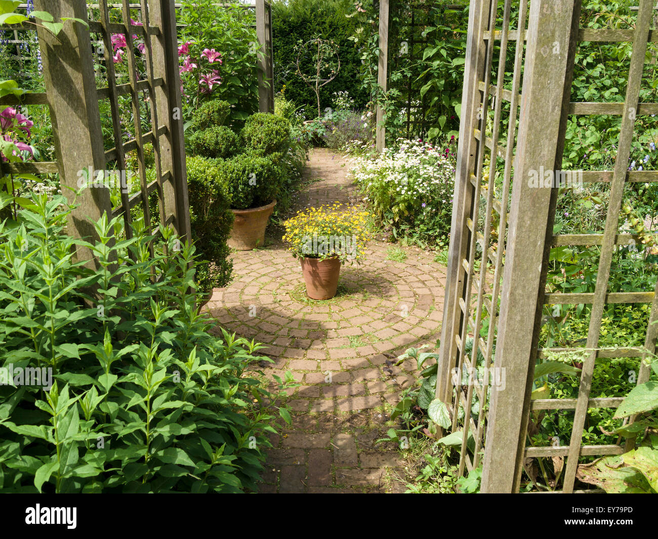Cottage garden with plants, trellis, brick paver paths and patio planters, Barnsdale Gardens, Rutland, England, UK. Stock Photo
