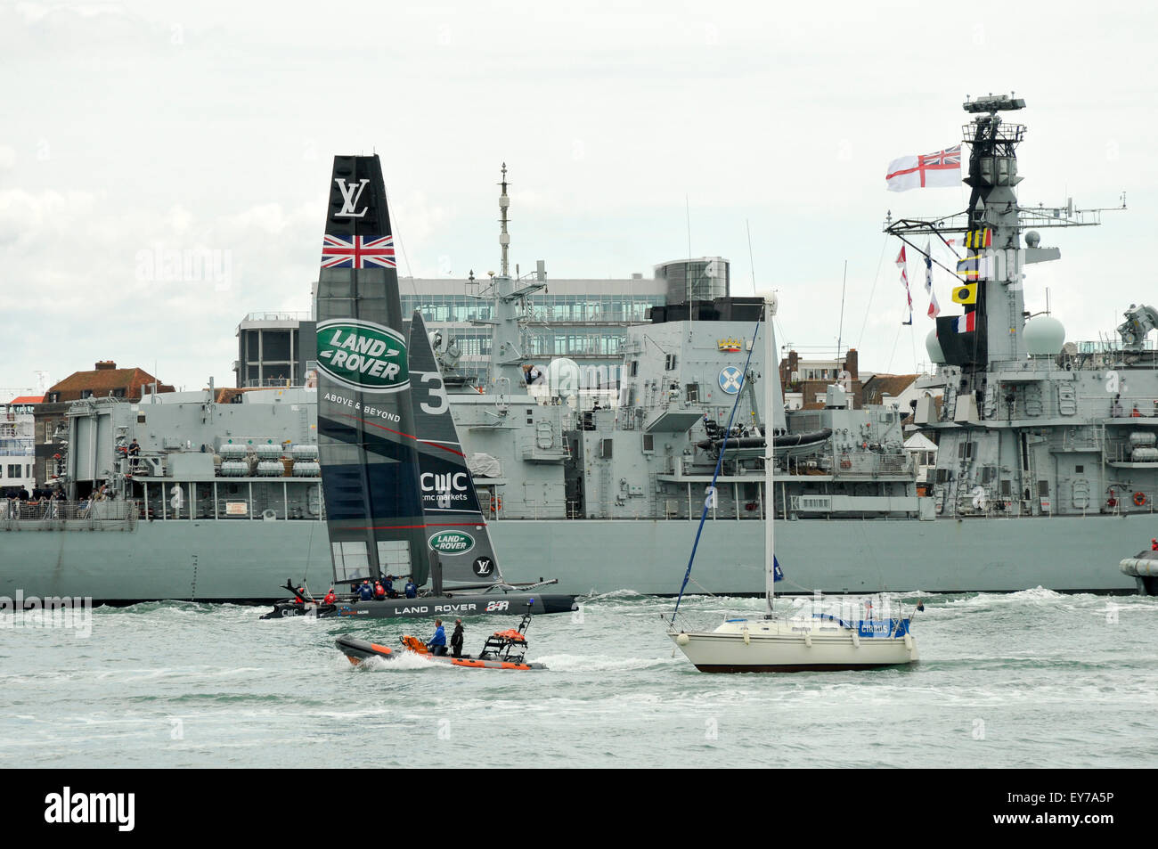 Portsmouth, UK. 23rd July, 2015. The Sail Past at the America’s Cup World Series Portsmouth. Sir Ben Ainslie at the helm of Land Rover BAR, the UK challenger alongside HMS St Albans as they leave Portsmouth Harbour. Credit:  Rob Wilkinson/ Alamy Live News Stock Photo