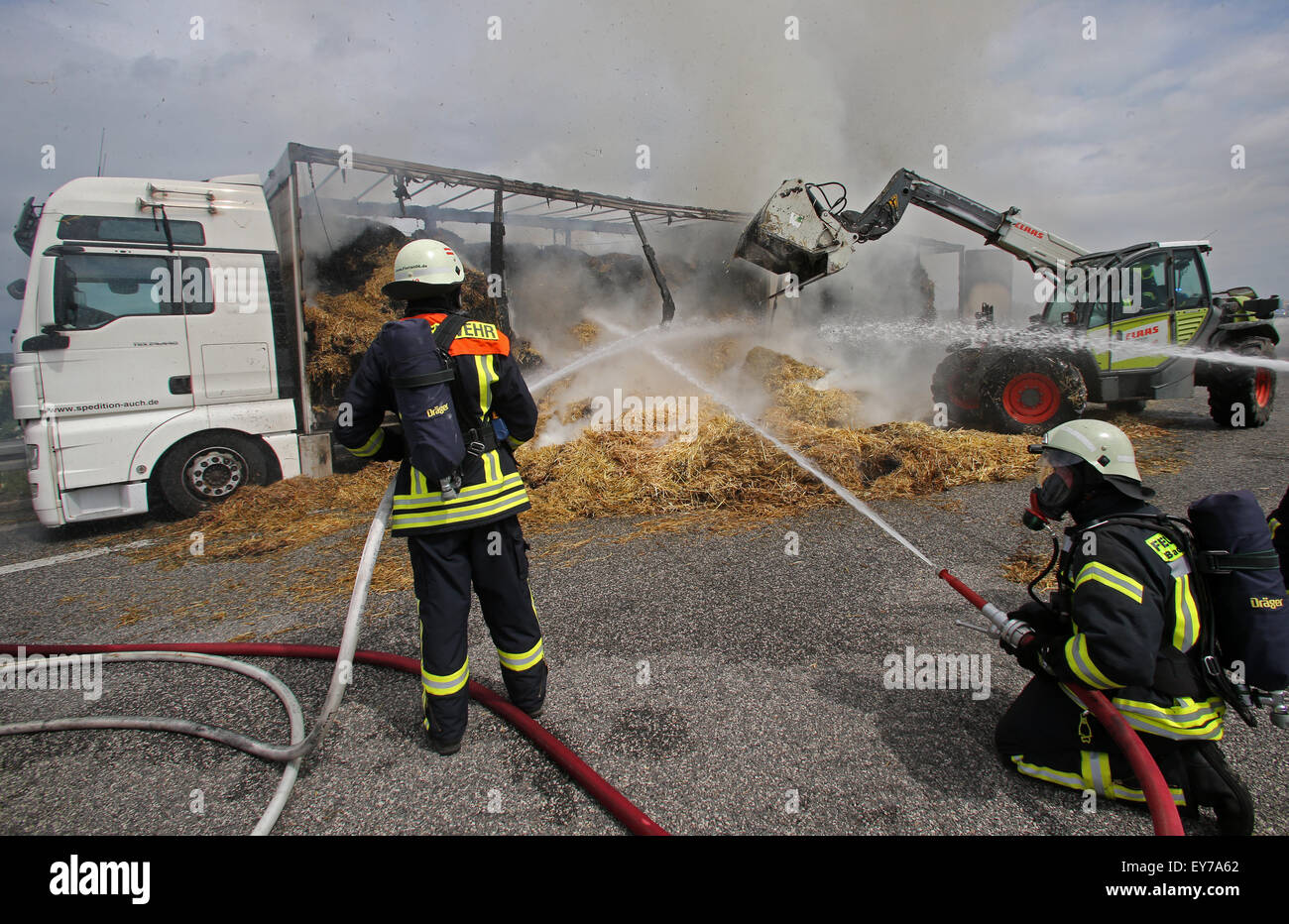 Rostock, Germany. 23rd July, 2015. Burning bales of straw on a truck on the A 20 motorway led to a major operation by the fire services near Rostock, Germany, 23 July 2015. The lanes between Bad Doberan and Kroepelin heading towards Luebeck were closed. PHOTO: BERND WUESTNECK/DPA/Alamy Live News Stock Photo