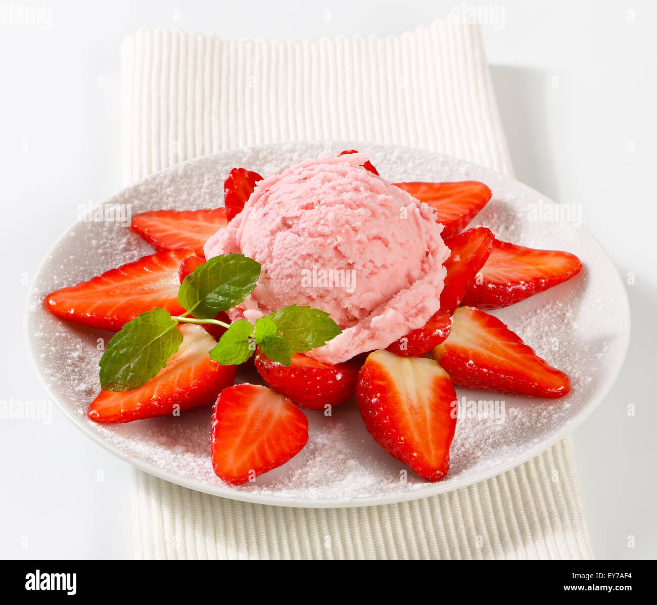 Fresh strawberries arranged around scoop of pink ice cream Stock Photo
