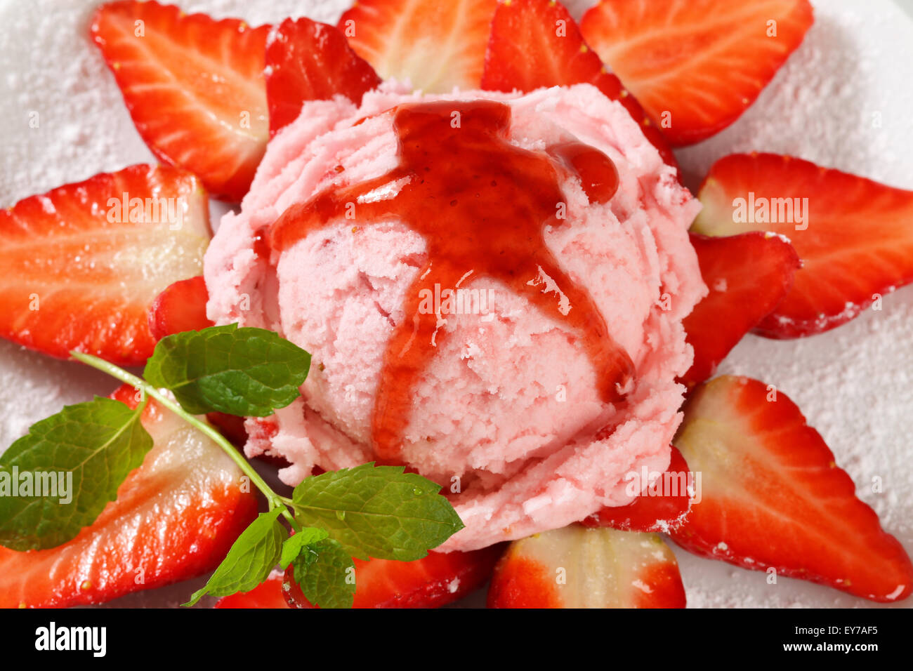 Fresh strawberries arranged around scoop of pink ice cream Stock Photo