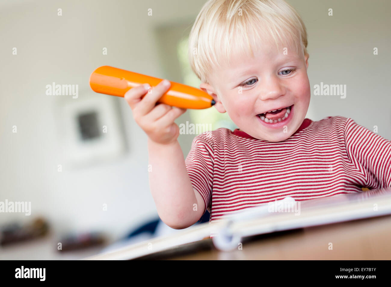 Young boy reading a childrens book with an electronic tiptoi pen, which explains the content of the book to the child. Stock Photo