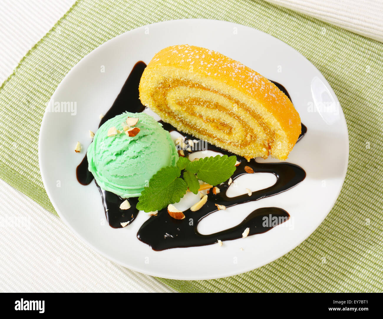Slice of Swiss roll cake with green sherbet and chocolate sauce Stock Photo