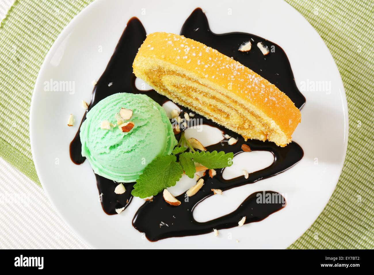 Slice of Swiss roll cake with green sherbet and chocolate sauce Stock Photo