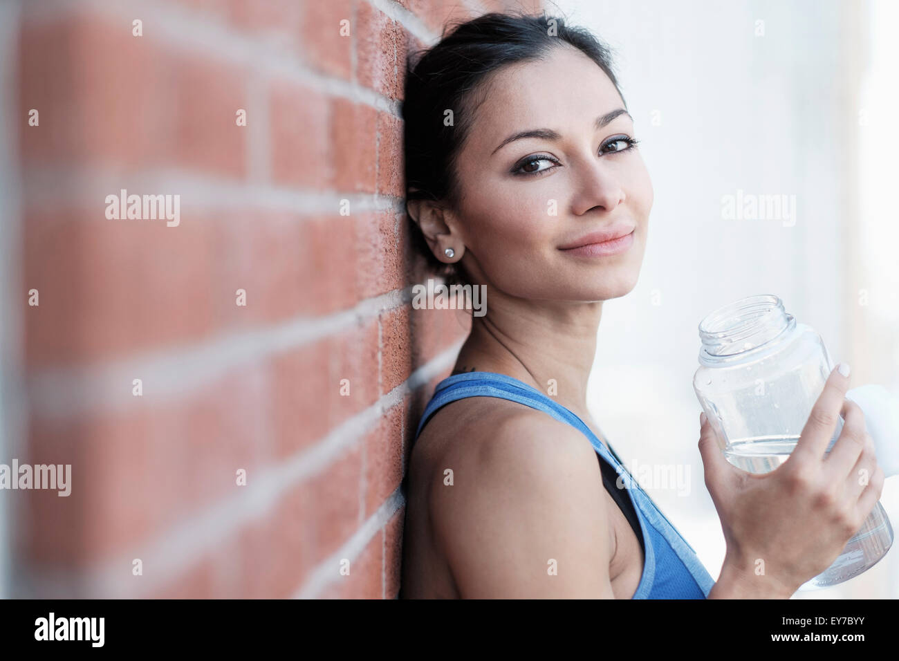 Portrait of young woman by brick wall Stock Photo