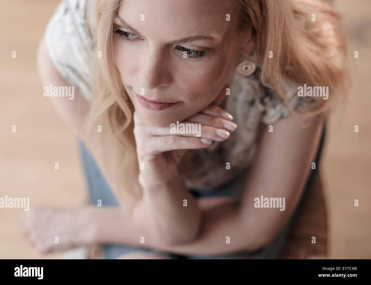 Mid-adult woman sitting on chair, thinking Stock Photo