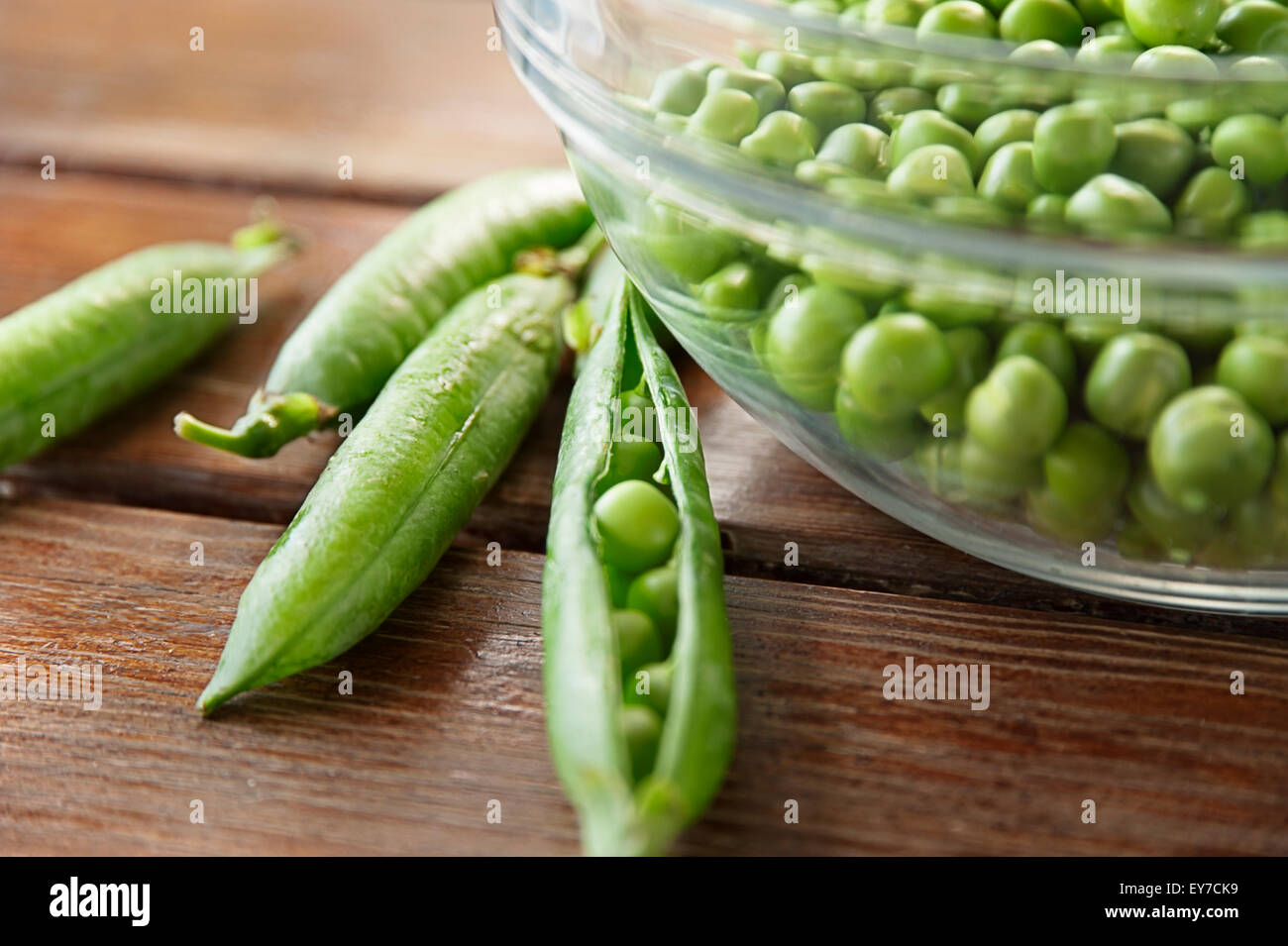 Pea pods and glass bowl full of peas Stock Photo