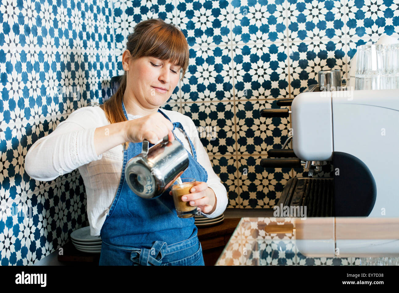 Female barista pouring coffee into glass Stock Photo