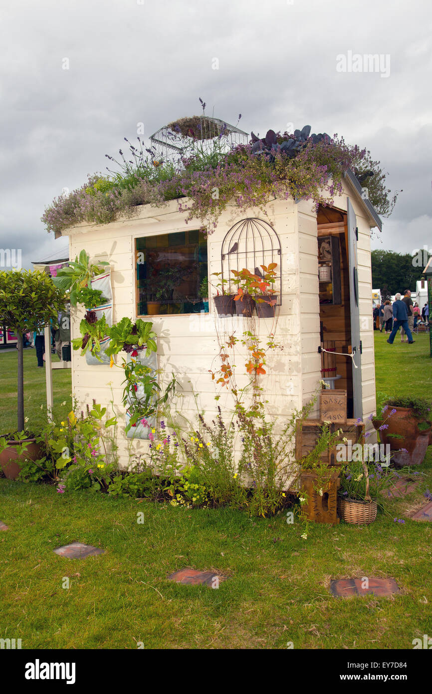 Funny gardeners wooden painted shed, weird garden or storage outdoor building, gardening tools and supplies bespoke sheds with heather roof at Tatton Park, Cheshire, UK July 2015.  The Lost Gardens of Manchester - DIY Garden sheds, personalised painted backyard shed design  Designer: Sean Harkin  RHS members day at the 17th  RHS Festival Flower Show. Stock Photo