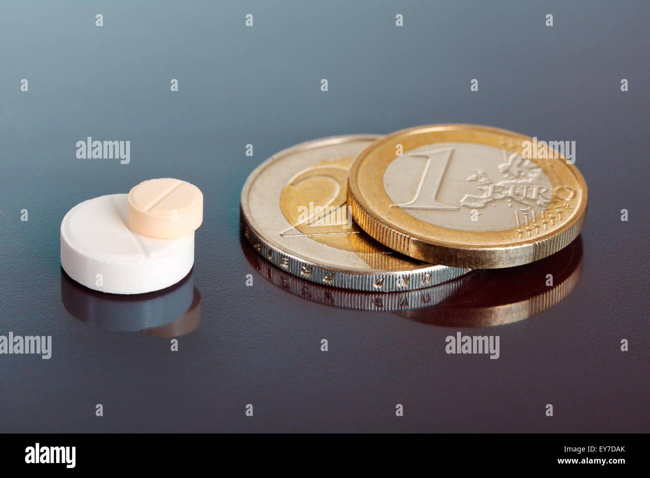 Closeup on pair of stacked pills near pair of similarly arranged euro coins Stock Photo