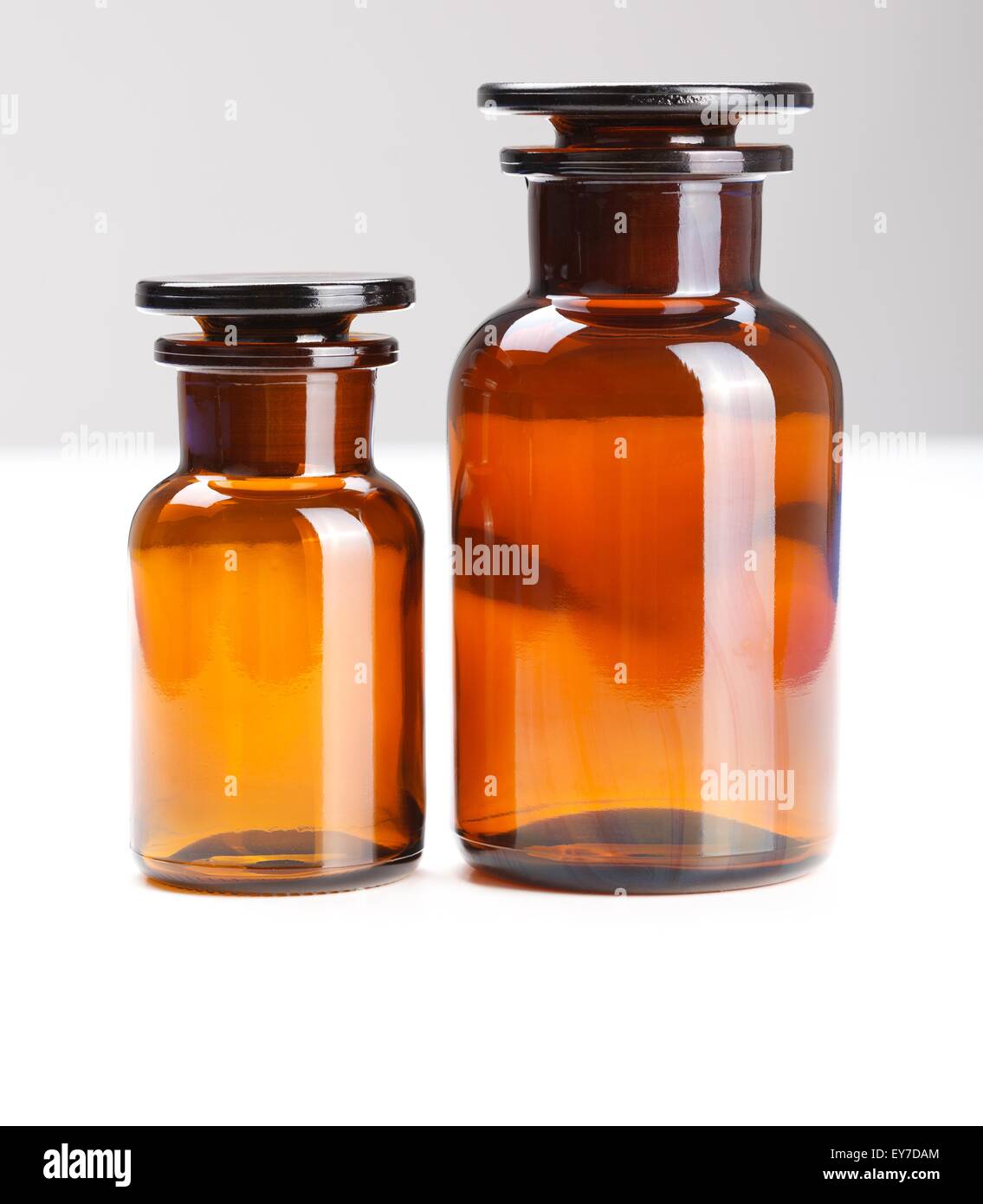 Two different sized chemical glass bottles standing close together