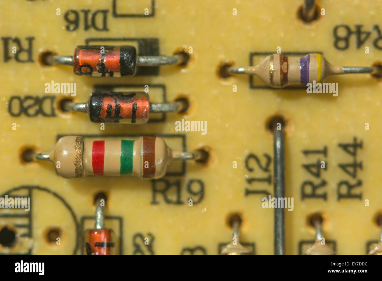 Macro-photo carbon resistors & diodes on traditional through-hole printed circuit board / PCB. Electrical resistance, circuit close up detail shot. Stock Photo