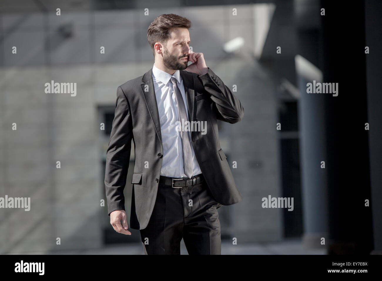 Businessman using phone outdoors Stock Photo