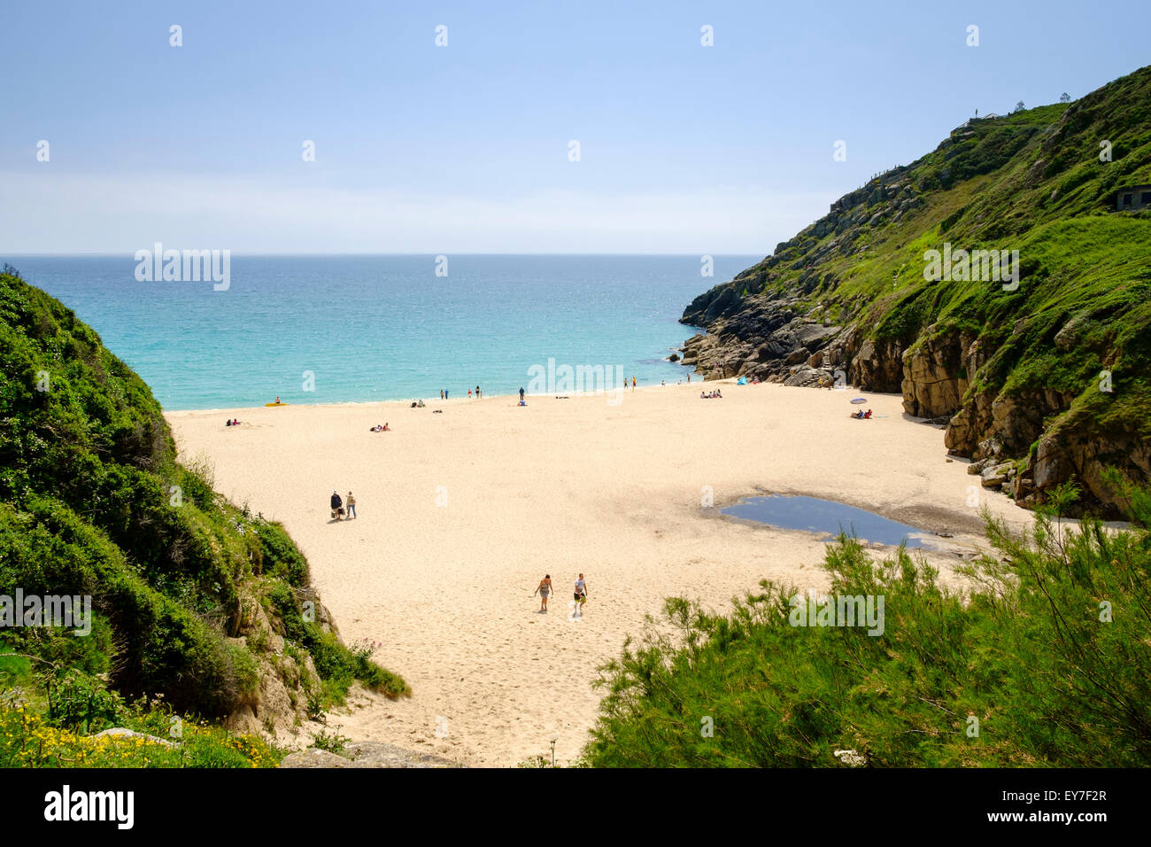 Summer, Cornwall, UK. People sunbathing on a beautiful summer day on a sandy beach in the cove at Porthcurno beach, Cornwall, UK Stock Photo