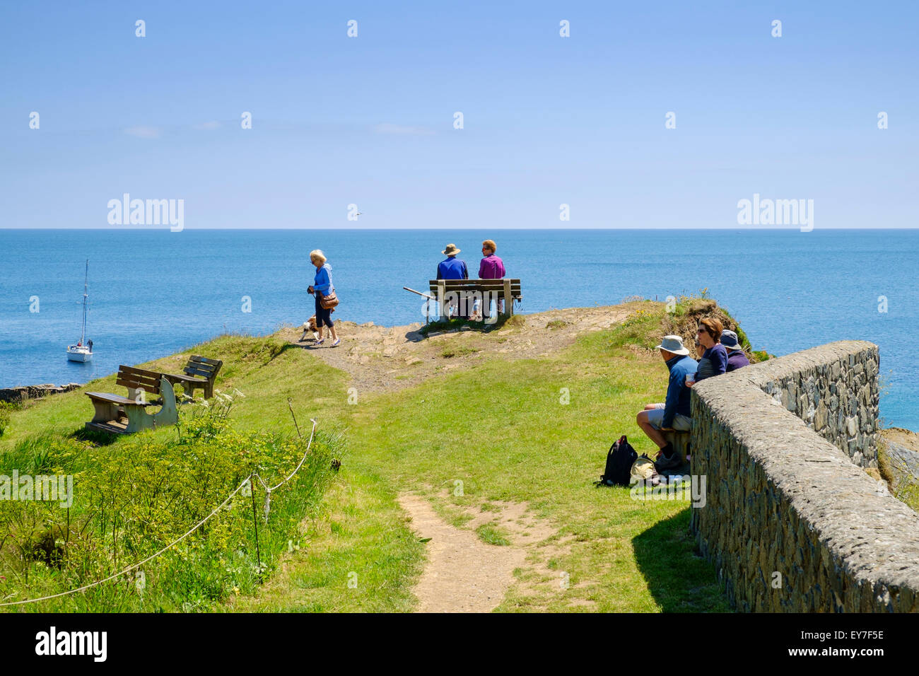Tourists looking out to sea on the harbor walls at Cadgwith, Lizard Peninsula, Cornwall, England, UK Stock Photo