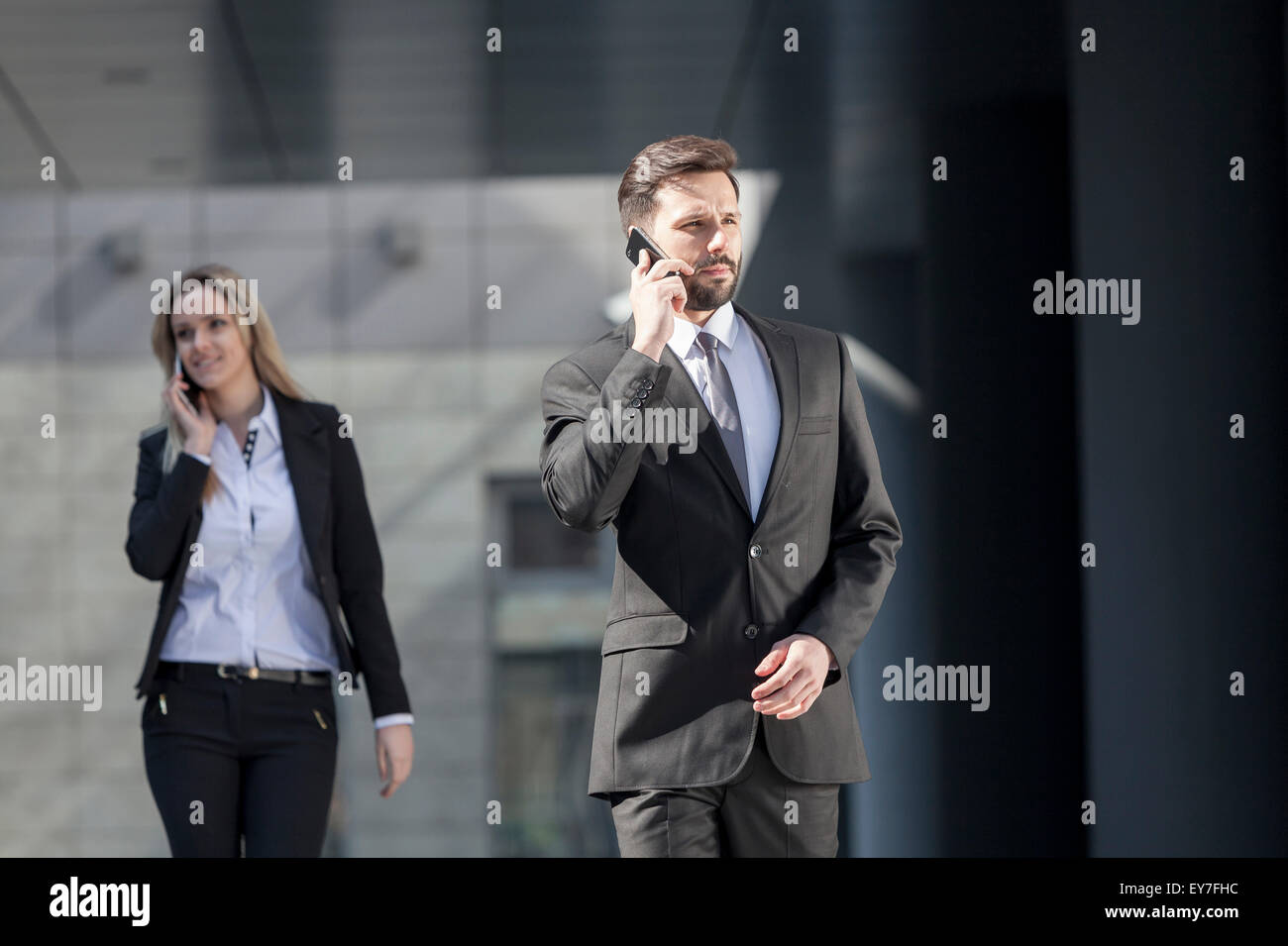 Business partners using phones outdoors Stock Photo